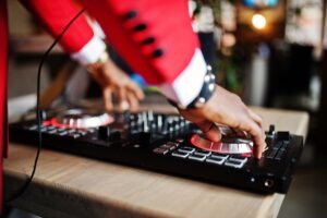 DJ w czerwonym garniturze przy konsolecie na weselu